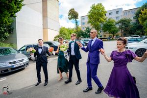 Group jumping and posing energetically in a parking area wearing formal attire.