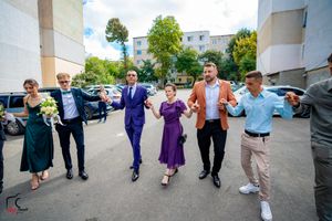 Wedding party members lined up and jumping in synchronized formation outdoors.