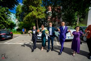 Wedding party members dancing in a line formation on a sunny day.