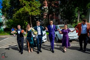 Formal-dressed group performing synchronized dance moves in an outdoor setting.