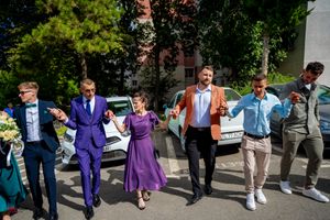 Wedding attendees doing a choreographed line dance in a parking area.