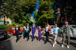 Group performing coordinated dance steps in purple and dark formal wear.