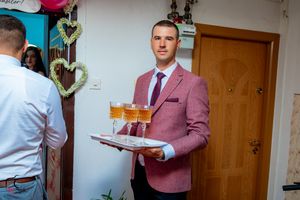 Indoor celebration with guests in formal attire serving refreshments.
