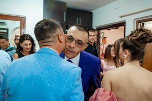 Wedding guests gather in a blue-walled room during a celebration.