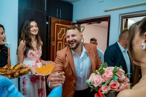 Guests at a wedding celebration share joyful moments with refreshments and pink roses.