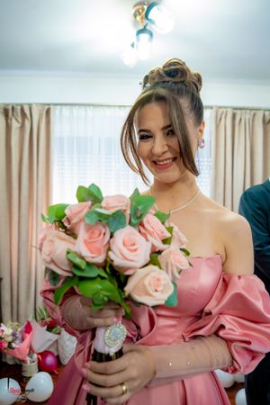 A pink rose bouquet held by someone in an off-shoulder pink dress.