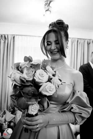 Black and white photo of someone holding a bouquet of roses in an elegant dress.