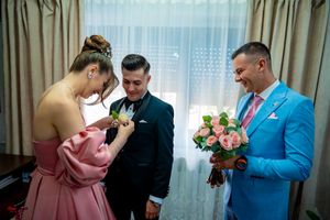 Three people in formal wear during a pre-wedding moment with pink roses and elegant decor.