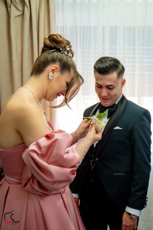 A tender moment during wedding preparations as boutonniere is adjusted.
