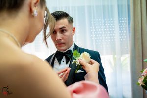 A close-up shot of boutonniere being pinned during wedding preparations.