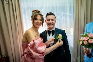 Wedding party members share joyful moment while pinning boutonnieres.