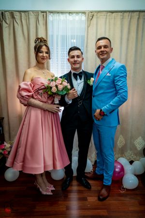 Wedding celebration group photo with bright blue suit and pink dress accents.