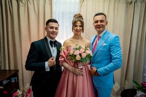 Wedding party members gather for formal photos in coordinated pink and blue attire.