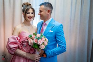 A joyful couple shares a moment in matching pink and bright blue formal wear.