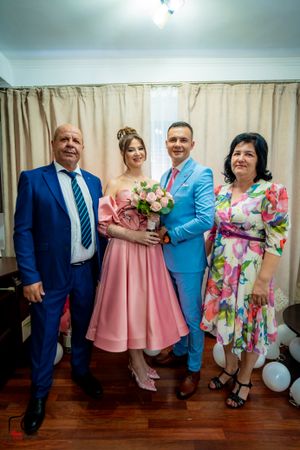 Family members gather for photos in coordinated blue, pink and floral outfits against cream curtains.