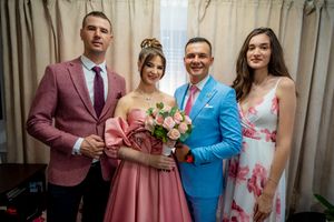Wedding party members pose together in a living room wearing bright colors and formal attire.
