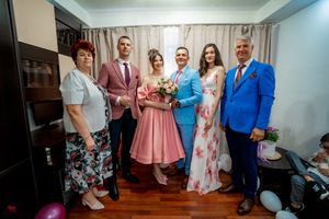 Panoramic shot of wedding party members posing in bright formal attire against light curtains.