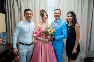 Wedding party poses in coordinated formal wear including a pink dress and bright blue suit.