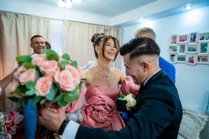 A couple shares a joyful moment at a wedding celebration with pink roses and formal attire.