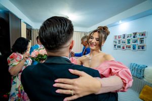Wedding celebration scene with guests in a room decorated with white curtains and floral arrangements.