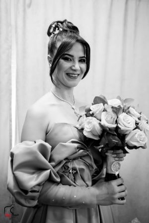 Black and white portrait showcasing an elegant off-shoulder gown with a rose bouquet.