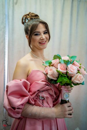 An off-shoulder pink dress paired with delicate pink roses creates a romantic bridal look.