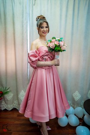 Pink satin dress with balloon sleeves photographed against blue balloons and white curtains.