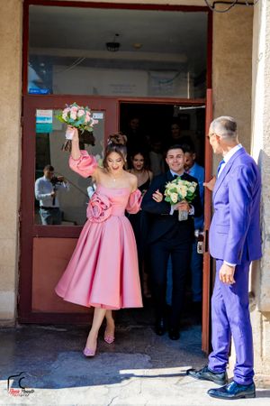 Wedding party gathering at a venue entrance with people in pink and purple attire.