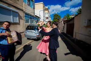 Celebratory dance moves captured in an urban setting with bright blue sky overhead.