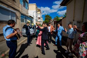 Wedding party dancing in formation on a city street with apartment buildings visible.