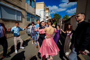 Festive group dancing outdoors in colorful attire during a wedding celebration.