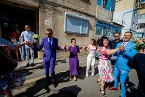 People in formal attire performing synchronized dance moves at an outdoor celebration.
