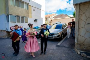 Street celebration with dancers in formal attire performing choreographed movements.