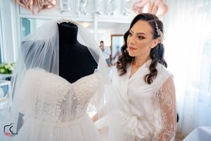 Elegant bridal preparation room with white wedding dress and rose gold decorations.