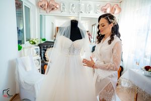 Bridesmaids in emerald green dresses gather around a white wedding gown in a bridal boutique.