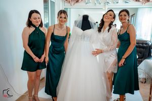 Wedding party members in emerald dresses share joyful moments while dress shopping.