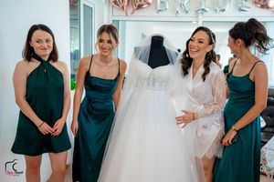 Bridesmaids in dark green attire share emotional moments during wedding dress shopping.