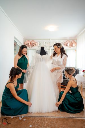 Bridesmaids in matching green dresses gather for candid moments in a bridal shop.