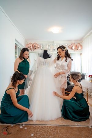 Wedding party members in dark green dresses share candid reactions during dress shopping.