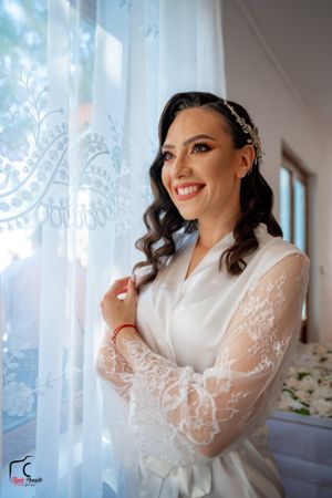 Elegant white bridal robe with lace sleeves photographed against sheer curtains.