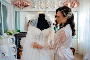 A bridal preparation room decorated with rose gold 'BRIDE' balloons and a white wedding dress on display.