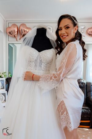 An elegant white wedding gown with intricate lace bodice displayed in a sunlit bridal suite.