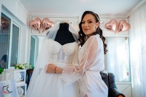 A pristine white wedding gown displayed in a bridal suite with rose gold decorative accents.