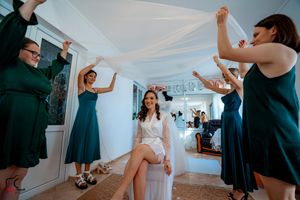 Wedding party preparations in a bright white room with people in navy blue dresses.