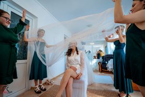 Wedding preparation scene with bridesmaids in navy dresses helping with final touches.