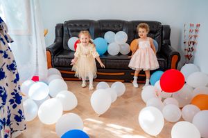 Wedding reception space decorated with white and red balloons against natural lighting.