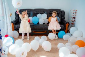 White and blue balloons decorating a room with party decor and furniture.