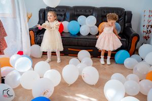 Children's party setup with white balloons and decorations in an indoor space.