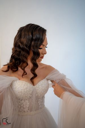 Side profile of a bride in an elegant white lace wedding gown with sheer sleeves.