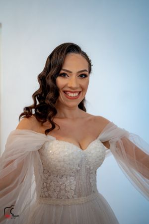 Radiant bride wearing a white lace wedding dress with off-shoulder sleeves.